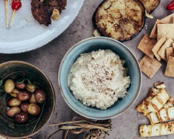 A variety of Mediterranean appetizers featuring hummus, olives, and grilled vegetables set on a rustic table.