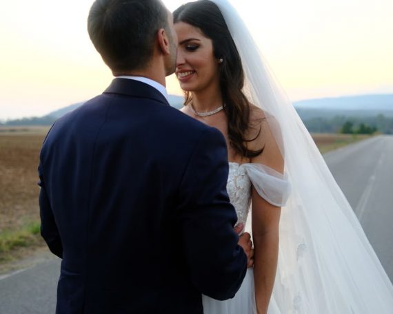 Bride and groom share a romantic moment on a country road at sunset.